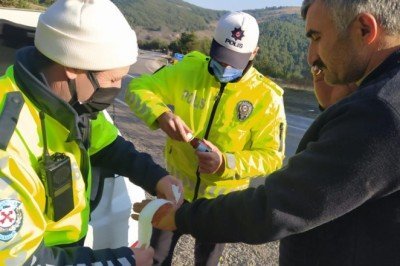 Polis devrilen tırdan çıkardığı sürücünün yaralanan elini sardı
